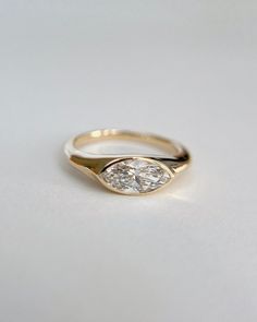 a yellow gold engagement ring with a pear shaped diamond in the center, on a white surface