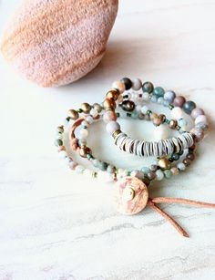 "First, at almost 22\" in length, this beaded strand can be worn as a necklace and a triple wrap bracelet if you like. Muted greens, grays, beige, gold, desert rose, touches of orange, rust, army green, beige, and more. A great mix of washed out color like a beaten ocean landscape. 6mm to 11mm Pearl, matte 4mm Moss Agate, matte Sunstone, matte 4mm  Jasper stones, and accents of seed beads, and metals. Distressed natural suede loops and coconut button closure make extendable. One-of-a-kind. The i Agate Bracelet With 108 Beads, Adjustable Hand-strung Jasper Jewelry, Agate Gemstone Beads Jewelry For Layering, Bohemian Jasper Bracelet, Adjustable Necklace For Layering, Adjustable Hand-strung Necklaces For Layering, Bohemian Style Layering Bracelets, Multi-strand Beaded Agate Jewelry, Bohemian Jewelry With Ocean Jasper Gemstone Beads