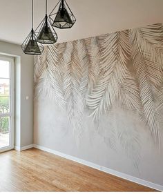 an empty room with wood flooring and large wall art on the walls, along with three hanging lamps