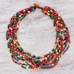 Thailand's Sumalee Nawakul puts together a palette of vibrant colors for the design of this necklace. She uses rice-shaped beads carved of littleleaf boxwood creating 10 hand-knotted strands that twist into a necklace. Multicolor Necklace With Oval Wooden Beads, Multicolor Wooden Beads Oval Necklaces, Multicolor Oval Wooden Beads Necklace, Multicolor Wooden Oval Beads Necklace, Traditional Multicolor Wooden Beaded Necklaces, Traditional Multicolor Wooden Beaded Necklace, Multicolor Oval Wooden Beads, Fair Trade Multi-strand Necklace As Gift, Fair Trade Multi-strand Necklace For Gift