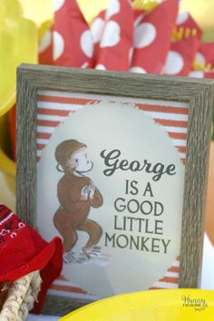 there is a sign that says george is a god little monkey on the table with other decorations