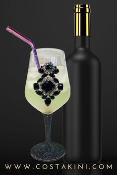 a wine glass with a drink in it and a bottle next to it on a black background