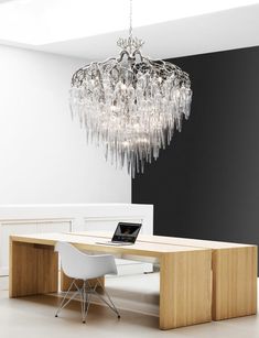 a chandelier hanging from the ceiling over a table with chairs and a laptop on it