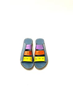 Vintage 1970s vegan leather lightweight foam sandals. Features dusty blue lightweight foam uppers, purple/orange/yellow vented straps at vamp, contrasting top stitching, slight foam wedge heel, and white rubber sole. Excellent vintage condition. Heel to toe (inside shoe): 8.75 inches Ball of foot (bottom of sole): 3.375 inches Heel height: 1.25 inches Size 5 (marked European size 35) Multicolor Rubber Sole Sandals For Summer, Retro Multicolor Sandals For The Beach, Retro Multicolor Open Toe Sandals, Multicolor Slip-on Sandals With Rubber Sole, Retro Open Toe Sandals With Rubber Sole, Multicolor Open Toe Sandals With Rubber Sole, Casual Rainbow Open Toe Sandals, Leather Multicolor Flip Flops For Spring, Multicolor Leather Flip Flops For Spring