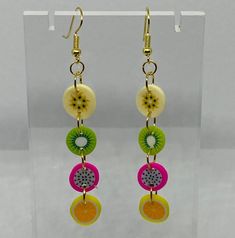 a pair of earrings with fruit and circles hanging from it's earwires