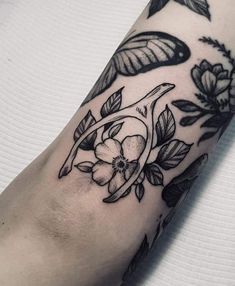 a close up of a person's arm with flowers and leaves on the wrist