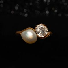 an image of two rings with pearls in them on a black background, one is gold and the other is white