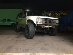 a white truck parked in a garage next to other cars and trucks on the ground