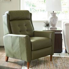 a green recliner chair sitting on top of a rug in front of a window