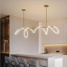 a modern kitchen with white cabinets and lights hanging from the ceiling, along with bar stools