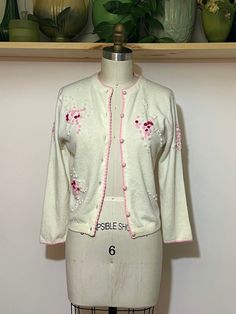 a mannequin wearing a white cardigan with pink flowers on the front and side