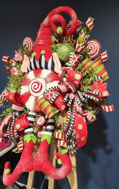 a christmas wreath with candy canes and santa hats on it, sitting on top of a wooden stand