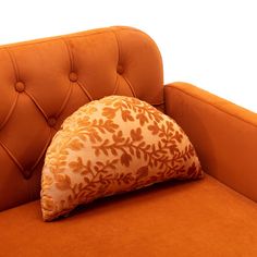 an orange couch with a decorative pillow on it's back and the seat upholstered