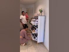 two people and a child are looking at shoes in a shoe rack on the floor