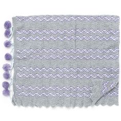 a gray and white blanket with purple pom poms