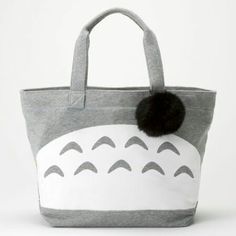 a gray and white tote bag with a black pom - pom on it