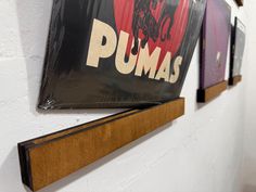 three framed pictures hang on the wall next to each other, one has a sign that says pumas