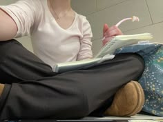 a woman sitting on the floor with a book in her lap and toothbrush in her mouth