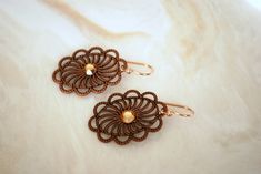 Unique filigree earrings that are great for everyday wear or special occasions. They dangle approximately 1 inch long. Made with bronze filigree frames and bronze Swarovski crystals, these earrings hang on Rose Gold French ear hooks with rubber backs. **Rose gold French ear hooks are made with a mixture of copper and gold. The copper gives the hooks a beautiful rosey color. Free gift wrapping at checkout! Please feel free to ask. *Update: The gift boxes are cuter than ever! They are now black an Elegant Brown Flower Earrings For Pierced Ears, Elegant Brown Drop Flower Earrings, Elegant Brown Flower Earrings For Gift, Elegant Brown Brass Earrings, Elegant Copper Filigree Jewelry, Elegant Bronze Copper Earrings, Copper Filigree Jewelry As A Gift, Elegant Copper Earrings For Gift, Elegant Rose Gold Copper Earrings