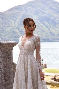 a woman in a wedding dress standing by the water