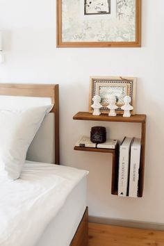 a bed with white sheets and pillows in a bedroom next to a framed picture on the wall