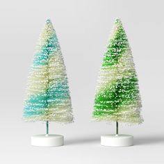 two small plastic christmas trees sitting on top of white bases