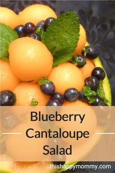 blueberry cantaloupe salad in a bowl with green leaves and oranges