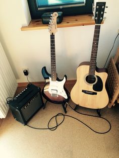 two guitars sitting next to each other in front of a tv and amps on the floor