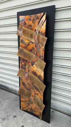 a metal sculpture sitting on top of a sidewalk next to a garage door and building