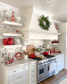 the kitchen is decorated for christmas with red and white decor on the counters, shelves, and stove