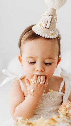 a baby wearing a party hat eating cake