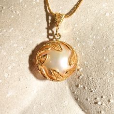 An ethereal 14k filigree mabe pearl pendant with an iridescent mother of pearl backing. The pearl cabochon has a lustrous reflection and sits inside an open back setting framed with a beautiful leaf overlay and suspended from a matching filigree bail. It looks like the mother of pearl cabochon has been glued to the back of the mabe pearl cabochon and is secured with gold prong clamps. Unfortunately one of the four prongs has broken off (see photos), but the pearl remains secure with only minimal Elegant White Medallion Pearl Necklace, Elegant Pearl Pendant Medallion Jewelry, Elegant Medallion Pearl Necklace With Pendant, Elegant Engraved Mother Of Pearl Jewelry, Elegant Gold Pearl Necklace With Intricate Design, Elegant Round Pearl Necklace With Intricate Design, Elegant Engraved Mother Of Pearl Necklace, Brooch Men, Diamonds In The Sky