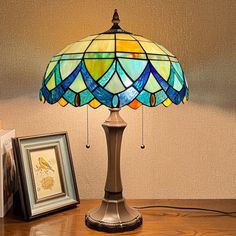 a lamp sitting on top of a wooden table next to two framed pictures and a painting