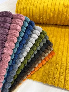 several colors of towels are stacked next to each other on a white counter top, with one folded over the edge