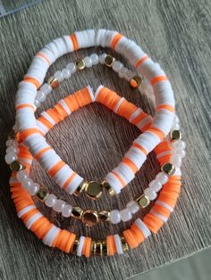 three bracelets with orange and white beads