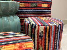 two colorful stools next to each other in front of a vase with flowers on it