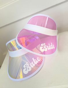 "Personalized Beach Visors are the perfect accessories for your pool or beach bachelorette party! Each holographic visor comes in your choice of Bride, Babe, or a custom name in white vinyl sure to make your bridal party stand out in style. ★DETAILS★ Listing is for 1 Personalized Holographic Visor. No Other Items Included. ★HOW TO ORDER MORE THAN ONE TEXT STYLE★ 1. Choose your style from the drop-down and add each hat to your cart one at a time. 2. Your shipping will automatically combine when ordering multiples. 3. Checkout out all at once when the correct color and qty have been added. ★HOW TO PERSONALIZE★ If You Chose the \"Custom\" Option Leave Your Text In The Provided Box. For example- Name: Annie Font: Babette Name: Ashley Font: Babette Name: Casey Font: Babette Name = 9 Characters Fun Pink Summer Party Supplies, Summer Fun Pink Party Supplies, White Summer Party Supplies, Adjustable Pink Party Supplies For Summer, Pink Visor For Summer Beach, Pink Summer Beach Visor, Adjustable Pink Visor For The Beach, Adjustable Pink Beach Visor, Adjustable Pink Visor For Beach