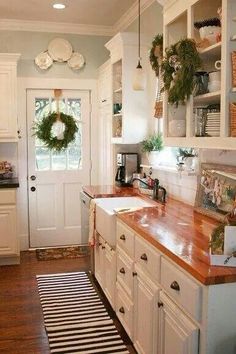 a kitchen with white cabinets and wooden counter tops, along with a black and white striped rug