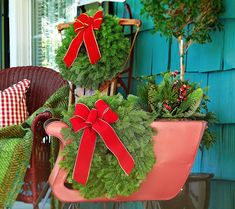 two christmas wreaths with red bows on them sitting in a pink sleigh