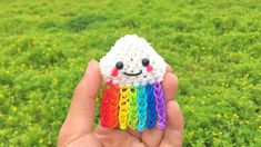 someone is holding up a small toy that looks like a sheep with rainbows on it