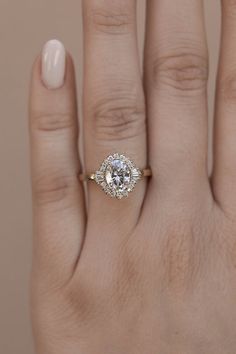 a woman's hand with a diamond ring on top of her finger and the other hand holding an engagement ring