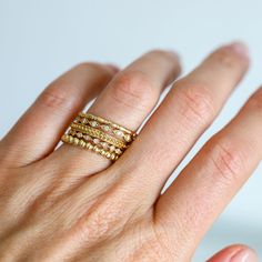 a woman's hand with three gold rings on her left and two different sized bands on her right