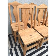 four wooden chairs sitting next to each other on a checkered black and white floor