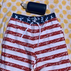 Red, White, And Blue Striped Draw String Waist Comfortable Beach Shorts With Flag Print, White Beach Bottoms For 4th Of July, White Bottoms For 4th Of July Beach Outing, Red Flag Print Shorts For Beach, Red Flag Print Beach Shorts, Patriotic Beach Shorts With American Flag Print, Casual Beach Bottoms With Flag Print, Casual Flag Print Bottoms For Beach, Casual Bottoms With Flag Print For Beach