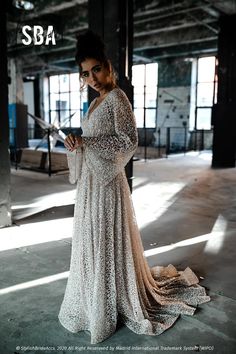 a woman in a long dress is holding a tablet