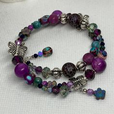 "This unique wrap bracelet is part of my FLUTTER DREAM Collection of jewelry, created in 2023 ~  This collection features themes of flight and fantasy such as butterflies, fairies, dragonflies, & wings, and has a vivid colour story of blue, green, purple, chromatics, iridescence, silver & a touch of gold. Any or all of the pieces in the entire collection were created to be worn together: Mix and match and have some fun!  Many lovely & unique combinations are possible. Create your own set by choo Adjustable Purple Bohemian Charm Bracelet, Adjustable Bohemian Jewelry With Butterfly Charm, Bohemian Butterfly Bracelets As Gift, Bohemian Butterfly Bracelet Gift, Bohemian Butterfly Bracelet, Whimsical Silver Beaded Adjustable Bracelets, Adjustable Silver Beaded Bracelet With Butterfly Charm, Unique Adjustable Purple Beaded Bracelets, Whimsical Handmade Purple Bracelets