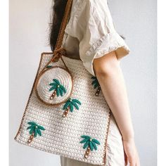 a woman carrying a white purse with green palm trees on it