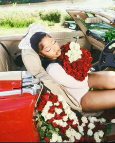 a woman sitting in the driver's seat of a car with flowers on it