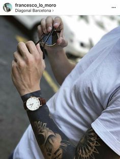 a man with tattoos on his arm holding up a pair of sunglasses