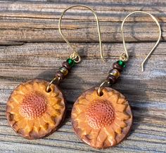 These earrings have a raised relief sunflower design which I've rubbed with yellow, orange and brown mica powders.  I've added small brown, yellow and green glass beads for accent.  The findings were made using 20G gold tone jewelry wire (Hildie & Jo, Wire Elements or Beadalon).  They measure 2 5/8" long by 1" wide.  These are really bright and cheerful earrings. Brown Dangle Flower Earrings, Brown Dangle Flower Earrings For Pierced Ears, Gold Sunflower Dangle Jewelry, Nature-inspired Brown Flower-shaped Jewelry, Artisan Orange Copper Earrings, Nickel-free Brown Beaded Earrings With Czech Glass, Nickel-free Brown Czech Glass Beaded Earrings, Handmade Brown Flower Jewelry, Adjustable Gold Sunflower Earrings